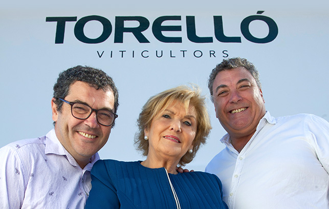 Torelló family photograph of three people (two men and one blond woman) very smilingossa al mig molt somrients