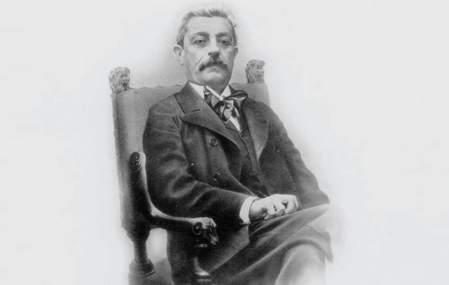 Black and white photograph of Marc Mir sitting on a chair